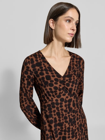 Frauenmodel trägt Midikleid mit V-Ausschnitt von zero in Braun mit schwarzem, großflächigem Muster, taillierte Passform, Nahaufnahme Oberkörper. Elastischer Material-Mix, langärmelig, glatte Textur, Kontext: Rückenlänge bei Größe 36 ca. 123 cm, Brustweite ca. 45 cm, Ärmellänge ca. 60 cm.