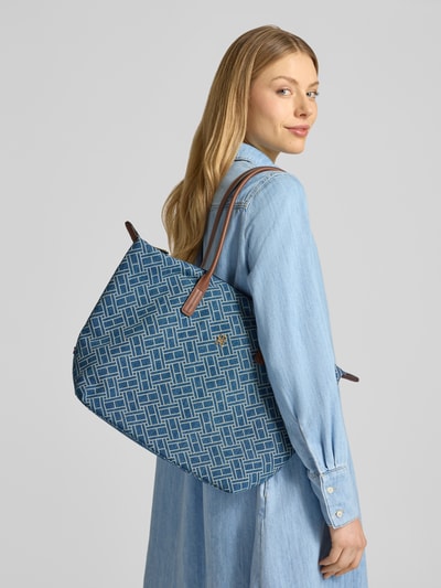 Frauenmodel trägt Shopper aus reiner Baumwolle von Tommy Hilfiger in Denim-Optik mit Logo-Muster und braunen Tragehenkeln, Nahaufnahme Oberkörper.