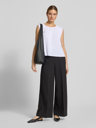 Frauenmodel trägt Loose Fit Blusentop aus Modal-Mix Modell 'FILLI' von Vero Moda, Optik: Unifarben, Passform: Loose-Fit, Rundhals-Ausschnitt, Ärmelform: Ohne, Materialverarbeitung: Stretch, Material: Modal-Mix, helle glatte Oberfläche, schwarze weite Hose, Ganzkörperansicht von vorne.