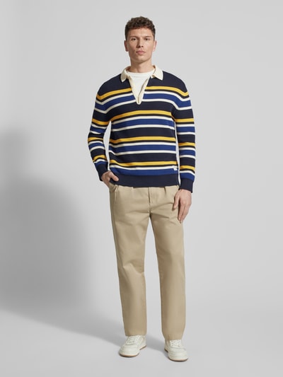 Männermodel trägt Strickpullover mit Polokragen und Label-Patch von Gant, gestreift in Blau, Weiß und Gelb, Baumwoll-Mix, Gerader-Schnitt, Rückenlänge 68 cm, Ärmellänge 66 cm, Ganzkörperansicht von vorne.