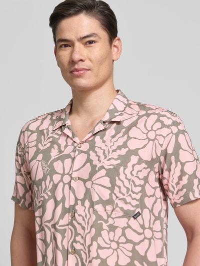 Männermodel trägt Freizeithemd im Allover-Look Modell 'Melo' von BOARDIES in Rosa und Beige mit floralem Muster, Nahaufnahme Oberkörper, Regular Fit, Reverskragen, Brusttasche, gefertigt aus reinen LENZING™ ECOVERO™ Fasern.