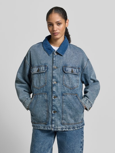 Frauenmodel trägt Jeansjacke mit Knopfleiste von American Vintage, reine Baumwolle, lockerer Schnitt, Kentkragen, Eingrifftaschen, Ganzkörperansicht von vorne.