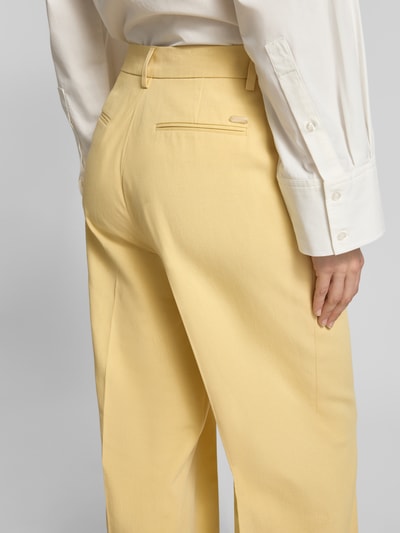 Frauenmodel trägt Wide Fit Stoffhose aus Lyocell-Mix Modell 'Edie' von Scotch & Soda in Gelb, glatte Textur, Rückansicht Nahaufnahme, Lyocell-Mix mit Baumwoll-Anteil, Bügelfalten und Gesäßtaschen