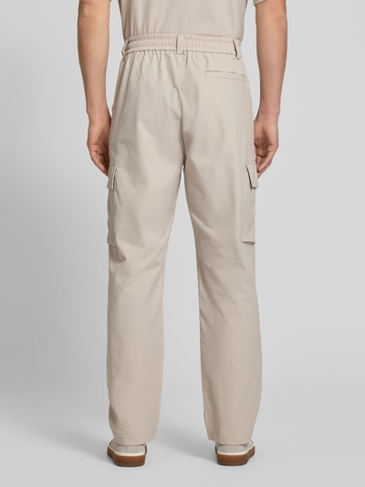 Männermodel trägt Relaxed Fit Cargohose mit Gürtelschlaufen Modell 'SRACKY' von BOSS Orange in Beige, unifarben, Ganzkörperansicht Rückansicht.