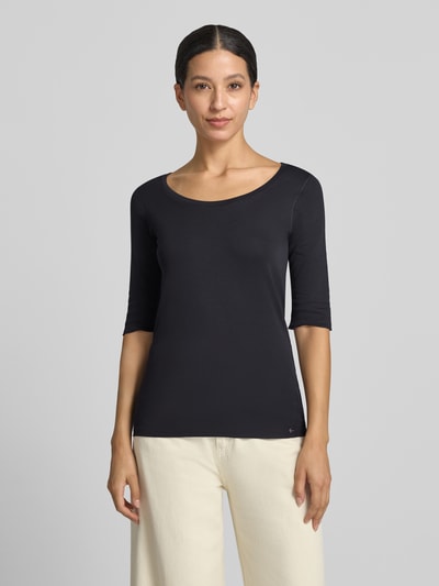 Modelka nosi T-Shirt mit Ärmelaufschlag und Rundhalsausschnitt von Marc Cain, mieszanka bawełny z dodatkiem streczu, dopasowany krój, okrągły dekolt, zakładka na rękawach, detal z logo, długość tyłu w rozmiarze 36: 60 cm, widok całej sylwetki z przodu.