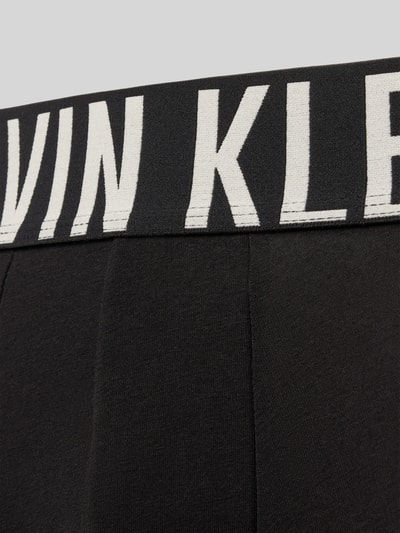 Produktfoto, schwarze Trunks aus Baumwoll-Mix mit großem weißen Label-Schriftzug am Bund, Calvin Klein Underwear.