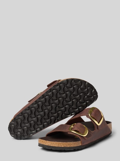 Produktfoto, Slides aus echtem Leder Modell 'Arizona' von Birkenstock in Braun mit breiten metallic Dornschließen, profilierter schwarzer Sohle, abgerundeter Form, offenem Design und 4 cm Absatzhöhe bei Größe 40