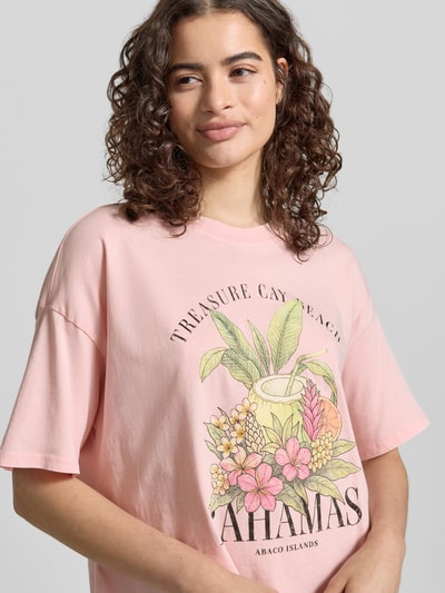 Frauenmodel trägt Boxy Fit T-Shirt aus reiner Baumwolle Modell 'LUCY' von Only, Optik: Unifarben, kurzarm, Rundhals, Motiv-Print vorne, Ganzkörperansicht von vorne.