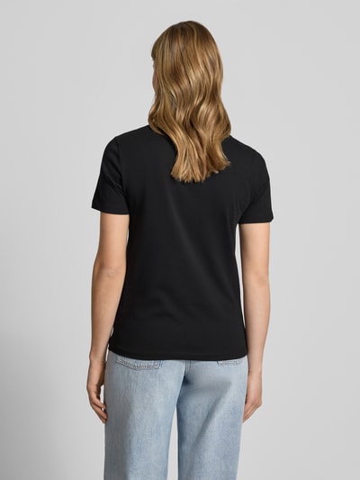 Frauenmodel trägt Damen T-Shirt aus reiner Baumwolle Modell 'KITA' von Only, Optik: Unifarben, Passform: Slim-Fit, Materialverarbeitung: Jersey, Farbe Schwarz, Kurzarm, Rundhals, Ganzkörperansicht Rückansicht.