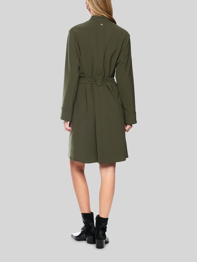 Frauenmodel trägt Knielanges Kleid mit Stehkragen und Gürtel von Marc Cain in Olivgrün, Material-Mix mit Stretch-Anteil, taillierter Schnitt, knielang, Stehkragen, Gürtel und lange Ärmel, Ganzkörperansicht Rückansicht.