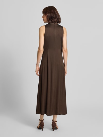 Frauenmodel trägt Maxikleid mit Stehkragen und Drapierungen Modell 'AMABEL' von DRYKORN in Braun, Material-Mix, Ganzkörperansicht Rückansicht.