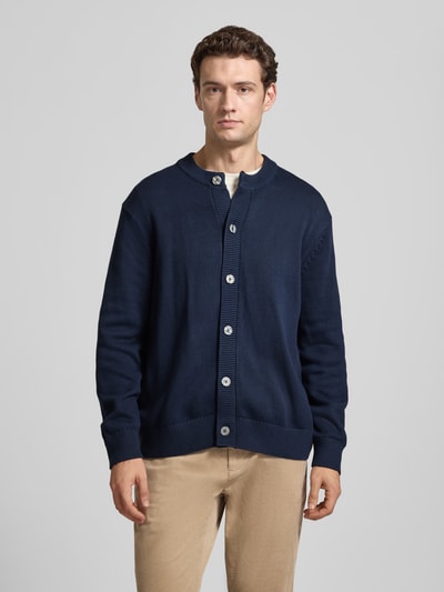 Männermodel trägt Regular Fit Cardigan aus reine Baumwolle von Selected in Dunkelblau, Rundhalsausschnitt, Knopfleiste, Rippenbündchen, Ganzkörperansicht von vorne.