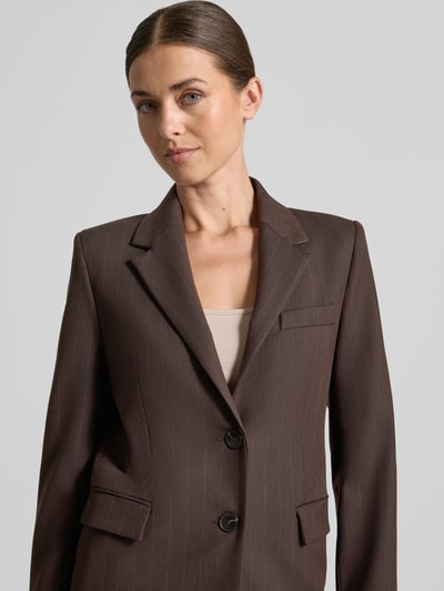Frauenmodel trägt Regular Fit Blazer mit Viskose-Anteil Modell 'Bergen' von MANGO in Dunkelbraun mit Reverskragen und Pattentaschen, Nahaufnahme Oberkörper.