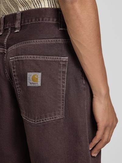 Męski model nosi szorty jeansowe z wpuszczanymi kieszeniami model 'Clark' od Carhartt Work In Progress z bawełny, krój relaxed fit, detal tylnej kieszeni, zbliżenie na dolną część pleców