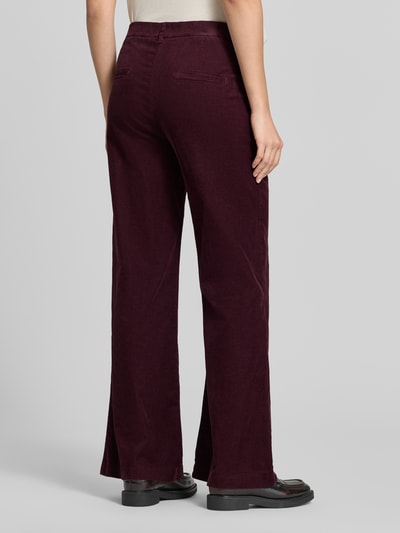 Männermodel trägt spodnie sztruksowe z mieszanki bawełny Wide Leg Cordhose aus Baumwoll-Mix Modell 'MAINE' von Brax w ciemnofioletowym kolorze, tekstura sztruksowa, Ganzkörperansicht Rückansicht, damskie spodnie sztruksowe marki Brax.