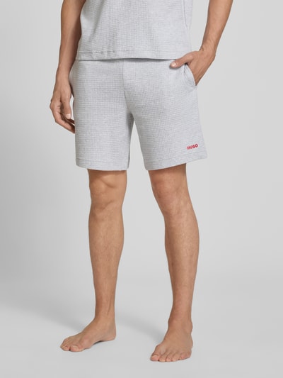 Männermodel trägt Regular Fit Sweatshorts aus Baumwoll-Mix Modell 'AUSTIN' von HUGO, hellgrau mit feiner Struktur, Nahaufnahme Oberschenkel, Herren Sweatshorts von HUGO.
