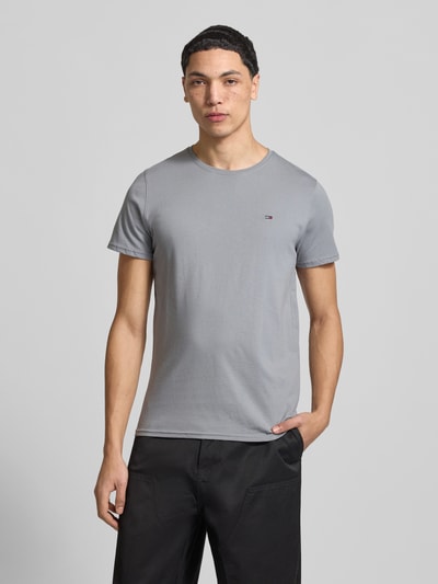 Männermodel trägt Regular Fit T-Shirt aus reiner Baumwolle von Tommy Jeans, Optik: Unifarben, Logo-Stitching, Ganzkörperansicht von vorne.