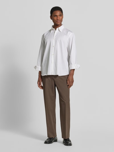 Mannelijk model draagt Straight Fit broek met viscose van MCNEAL in bruin, met bandplooien en achterzakken, elastische materiaalmix, knoop- en ritssluiting, bandwijdte maat M 41 cm, binnenbeenlengte 75 cm. Ganzkörperansicht van voren.