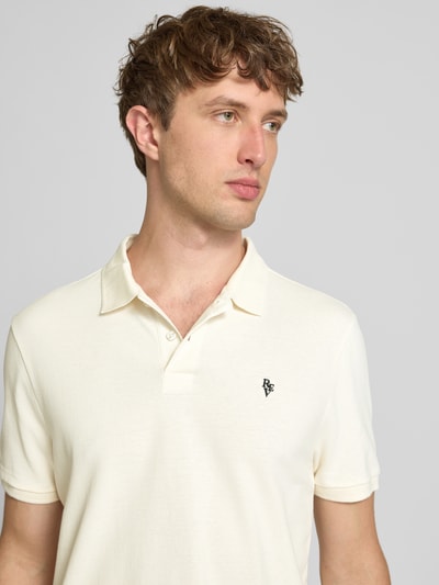 Männermodel trägt Modern Fit Poloshirt mit Logo-Stitching von REVIEW aus Baumwoll-Mix in Creme mit Polokragen, Nahaufnahme Oberkörper. Rückenlänge bei Größe M 65 cm.