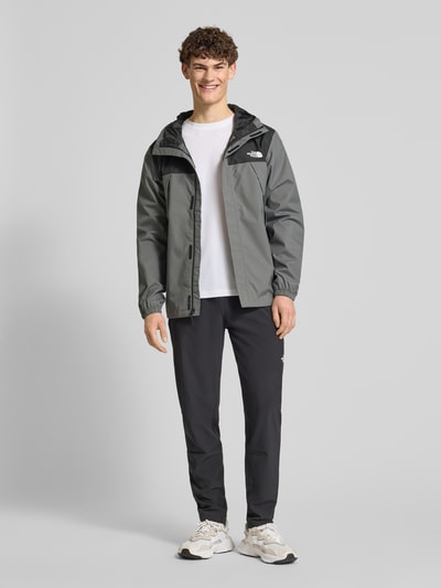 Męski model nosi Regular Fit Jacke mit Logo-Print Modell 'Antora' od The North Face, szaro-czarna, kieszenie, kaptur, całkowity widok z przodu, długość tyłu w rozmiarze M: 74 cm, szerokość ramion w rozmiarze M: 47 cm, szerokość klatki piersiowej w rozmiarze M: 58 cm, długość rękawa w rozmiarze M: 68 cm, krój regular fit