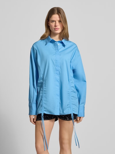 Frauenmodel trägt Oversized Bluse mit Kordelzug und verdeckter Knopfleiste von Karo Kauer, Reine Baumwolle, Oversized-Fit, Hemdblusenkragen, Sportmanschetten, Bund mit Kordelzug, Label-Patch, Rückenlänge 75 cm, Ärmellänge 61 cm, Himmelblau mit glatter Textur, Ganzkörperansicht von vorne.
