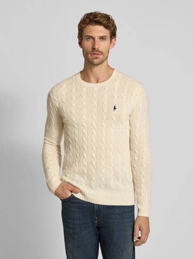 Männermodel trägt Regular Fit Pullover aus Woll-Kaschmir-Mix von Polo Ralph Lauren in creme mit Zopfmuster, Ganzkörperansicht von vorne. Herren Pullover von Polo Ralph Lauren