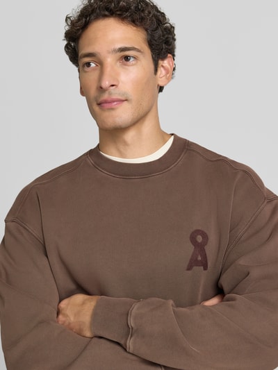 Männermodel trägt braunes Relaxed Fit Sweatshirt aus reiner Baumwolle Modell 'ICONIC Å' von ARMEDANGELS, Nahaufnahme Oberkörper. Herren Sweatshirt.