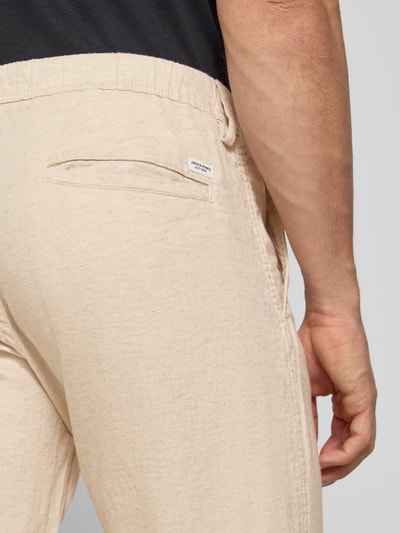 Männermodel draagt Relaxed Fit heren broek van mix van katoen en linnen model 'KANE' van Jack & Jones, beige, achterzak, detailaufnahme. Context: elastische band, vetersluiting, achterzakken, bandwijdte maat M 42 cm, binnenbeenlengte maat M 82 cm.