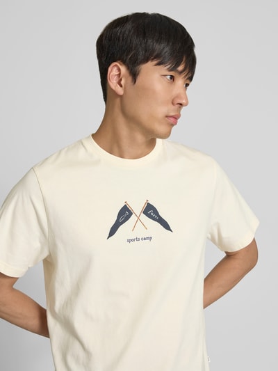 Männermodel trägt Regular Fit T-Shirt mit Logo-Print von Forét in Creme mit Rundhalsausschnitt, reine Baumwolle, Nahaufnahme Oberkörper.