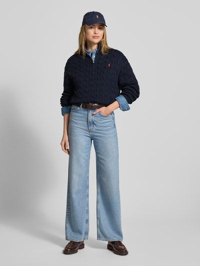 Vrouwenmodel draagt Troyer met Zopfstrickmuster van Polo Ralph Lauren in donkerblauw, puur katoen, regular fit, kabelpatroon, opstaande kraag met ritssluiting, gestikt logo, elastische boorden, ruglengte 53 cm, mouwlengte 55 cm, vooraanzicht hele lichaam.