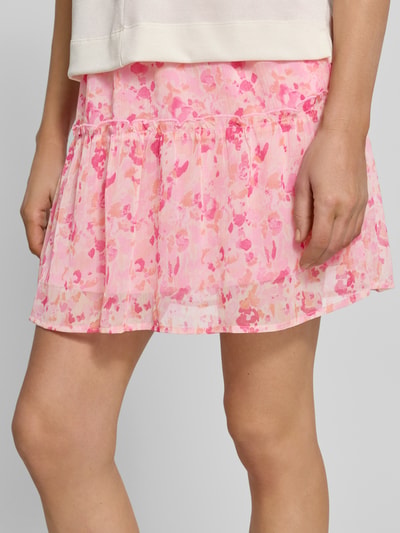 Vrouwenmodel draagt minirok met elastische band model 'EMMA' van Vila in A-lijn all-over look, roze tinten, detailopname onderlichaam.