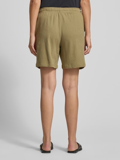 Vrouwenmodel draagt Shorts met zij-steekzakken van Fynch-Hatton, loose fit, elastische band met trekkoord, labeldetail, bermudalengte, bandwijdte maat S: 41 cm, binnenbeenlengte maat S: 20 cm, effen kaki, zachte textuur, ganzebody-achteraanzicht.