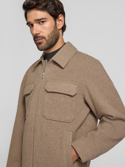 Männermodel trägt Regular Fit Hemdjacke mit Brusttaschen Modell 'WAKEFIELD' von JACK & JONES Premium, Kentkragen, Reißverschluss, beżowy kolor, Ganzkörperansicht von vorne, długość pleców w rozmiarze M: 66 cm.