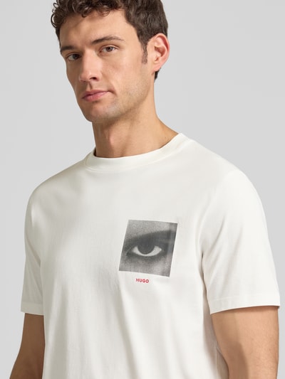 Männermodel trägt Regular Fit T-Shirt aus reiner Baumwolle Modell 'DEYSS' von HUGO in Optik: Unifarben, Motiv-Print, Nahaufnahme Oberkörper.