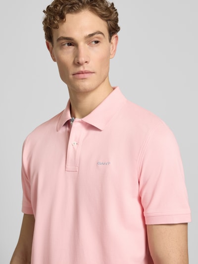 Mannelijk model draagt Regular Fit Poloshirt met Logo-Stitching van Gant, elastische katoenmix, lichtroze kleur, korte mouwen, polokraag, detailopname bovenlichaam.