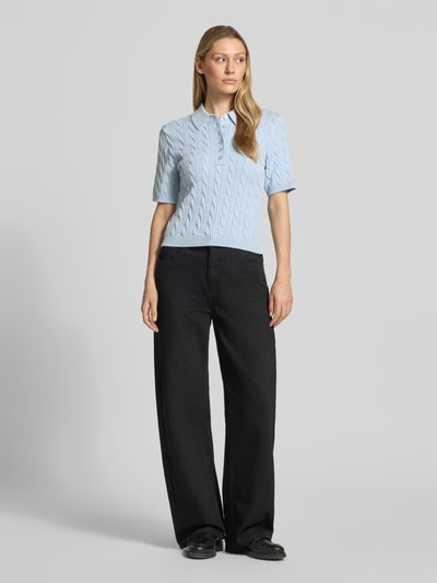 Frauenmodel trägt Slim Fit Poloshirt aus Viskose-Mix Modell 'Thilla' von Gestuz in Hellblau mit Strick-Optik und elastischen Abschlüssen, Ganzkörperansicht von vorne. Rückenlänge 51 cm, Halbarm, Ärmellänge 25 cm, Damen Poloshirt.