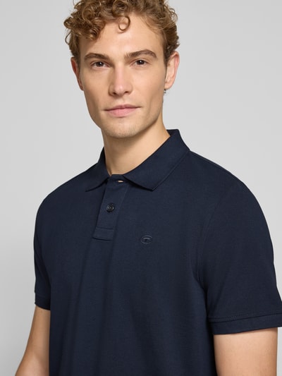 Männermodel trägt Regular Fit Poloshirt aus Baumwoll-Mix von Tom Tailor, dunkelblau, glatte Struktur, Herren Poloshirt, Nahaufnahme Oberkörper.