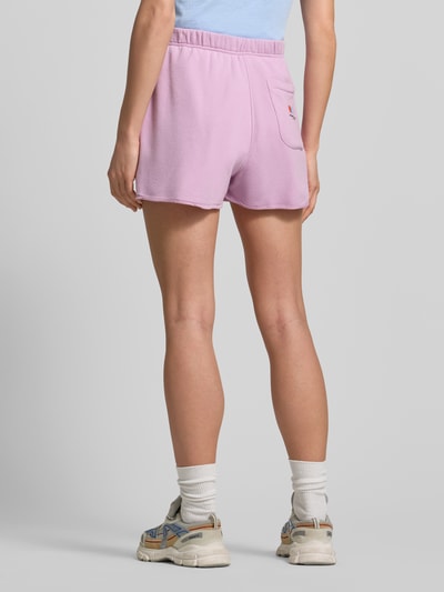 Vrouwenmodel draagt roze Sweatshorts met elastische tailleband model 'TUBAY' van American Vintage, katoen-elastaan mix, rechte fit, achterzak, zijzakken, binnenbeenlengte maat S 9 cm, volledige lichaamsaanzicht achteraan.