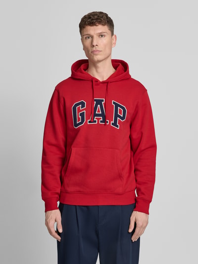 Mannelijk model draagt Hoodie met kangoeroezak van GAP in rood met labelstitching, katoenmix, losse pasvorm, ribboorden, voorkant, geheel lichaam.