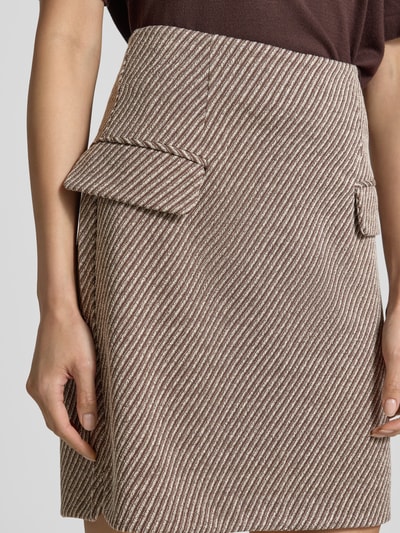 Kobieta nosi spódnica mini z elastycznej mieszanki materiałów z dodatkiem wiskozy, Linia a, Kieszenie z patką, fakturowany wzór, Model 'Kate' od ICHI, Szerokość w rozmiarze S: 38 cm, całkowita długość w rozmiarze S: 49 cm, zbliżenie na górną część.