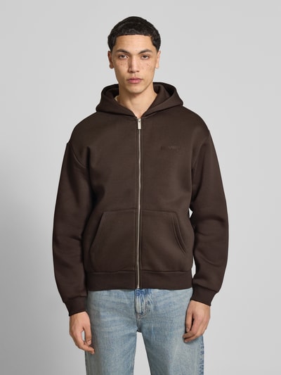 Männermodel trägt Sweatjacke mit Känguru-Tasche von REVIEW in Braun, aus Baumwoll-Mix, Relaxed-Fit, mit Reißverschluss, Ganzkörperansicht von vorne. Rückenlänge bei Größe M 68 cm, Ärmellänge bei Größe M 62 cm.