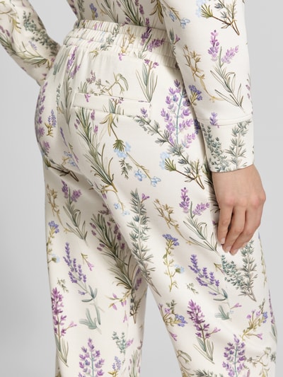Frauenmodel trägt Regular Fit Sweatpants aus Viskose-Mix mit verkürzter Passform von Christian Berg Woman, floraler Allover-Print, Gesäßtaschen, elastischer Bund, Nahaufnahme Rückansicht.