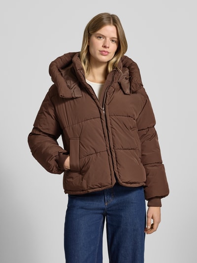 Frauenmodel trägt Regular Fit Steppjacke mit Kapuze Modell 'CORNELIA' von Only, unifarbene braune Optik, lange Ärmel, Ganzkörperansicht von vorne.