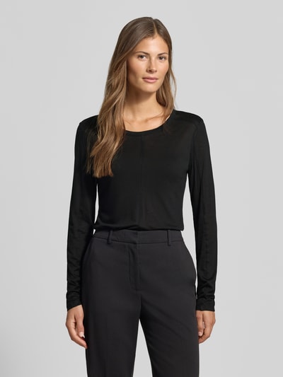 Frauenmodel trägt Longsleeve in semi-transparenter Optik von MYON, Lyocell-Mix mit Woll-Anteil, Schwarz, Rundhalsausschnitt, Ganzkörperansicht von vorne.