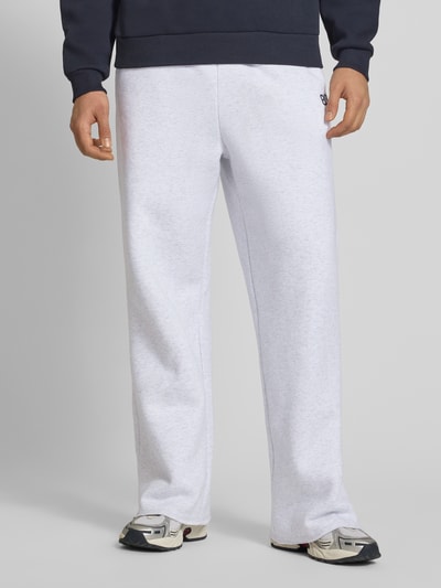 Männermodel trägt Straight Leg Sweatpants mit elastischem Bund von KARL KANI in Hellgrau, Baumwoll-Mix, Gesäßtasche, Ganzkörperansicht von vorne.