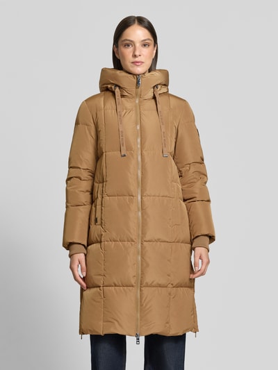 Frauenmodel trägt Regular Fit Mantel in Stepp-Optik Modell 'Nova' von MOS MOSH in Camel mit Kapuze und Zweiwege-Reißverschluss, Ganzkörperansicht von vorne. Damen Mantel mit Tunnelzug, Eingrifftaschen, Rückenlänge 102 cm, Schulterbreite 42 cm, Brustweite 46 cm, Ärmellänge 64 cm.