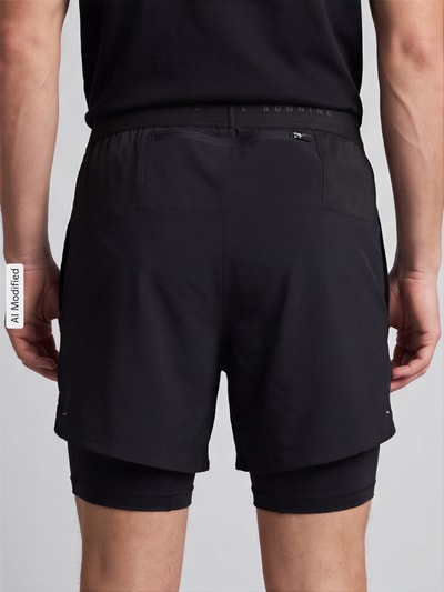 Männermodel trägt schwarze Regular Fit Sportshorts mit Dri-FIT-Technologie Modell 'STRIDE 5IN HYBRID' von Nike, Herren Sportshorts, Ganzkörperansicht Rückansicht, KI-modifiziertes Bild.