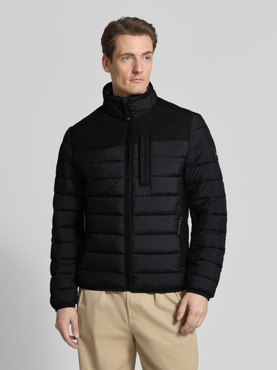Männermodel trägt Regular Fit Steppjacke mit seitlichen Stretcheinsätzen von Tom Tailor, Optik: Unifarben, Ganzkörperansicht von vorne.