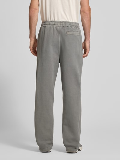 Männermodel trägt Loose Fit Sweatpants aus Baumwoll-Mix mit Label-Detail von PEGADOR in Grau, elastischer Bund, Eingrifftaschen, Ganzkörperansicht Rückansicht.