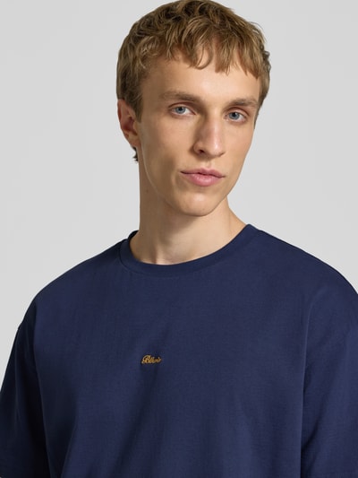 Mannenmodel draagt Regular Fit T-Shirt met Logo-Stitching van BLKVIS, donkerblauw, katoen, ronde hals, logo op de borst, close-up bovenlichaam.